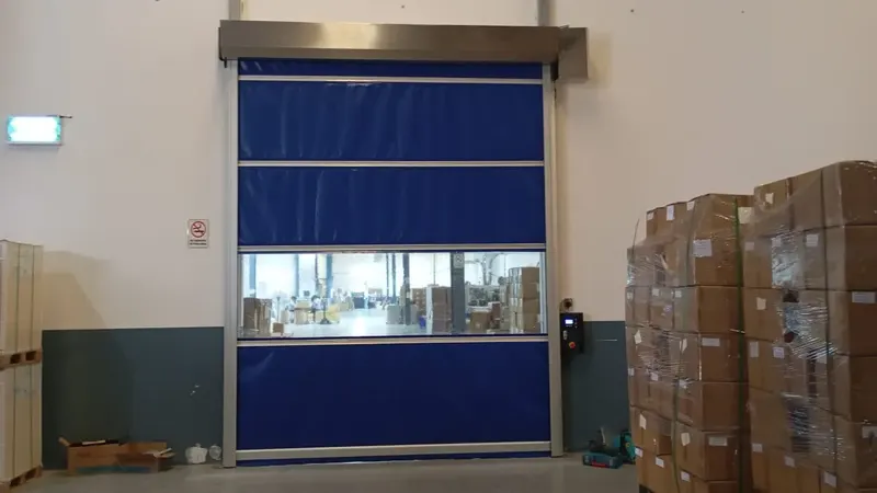 Blue high speed roll up door with vision panel and control box at a facility في Dubai Industrial City