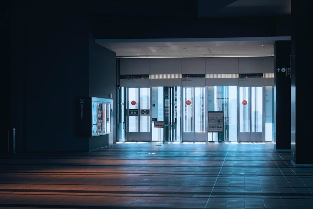 Modern building entrance with automatic glass doors and sunlight.